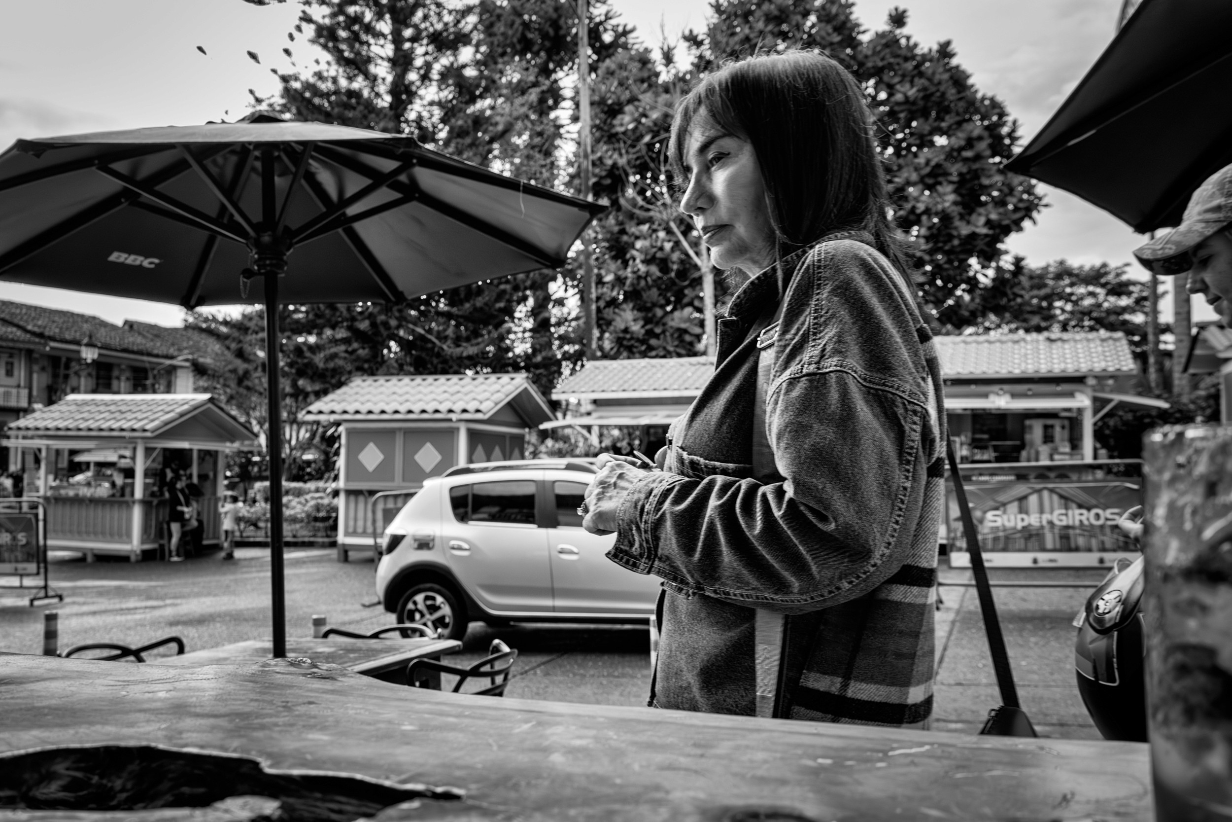 Rainy street scene with people passing by a bar window.