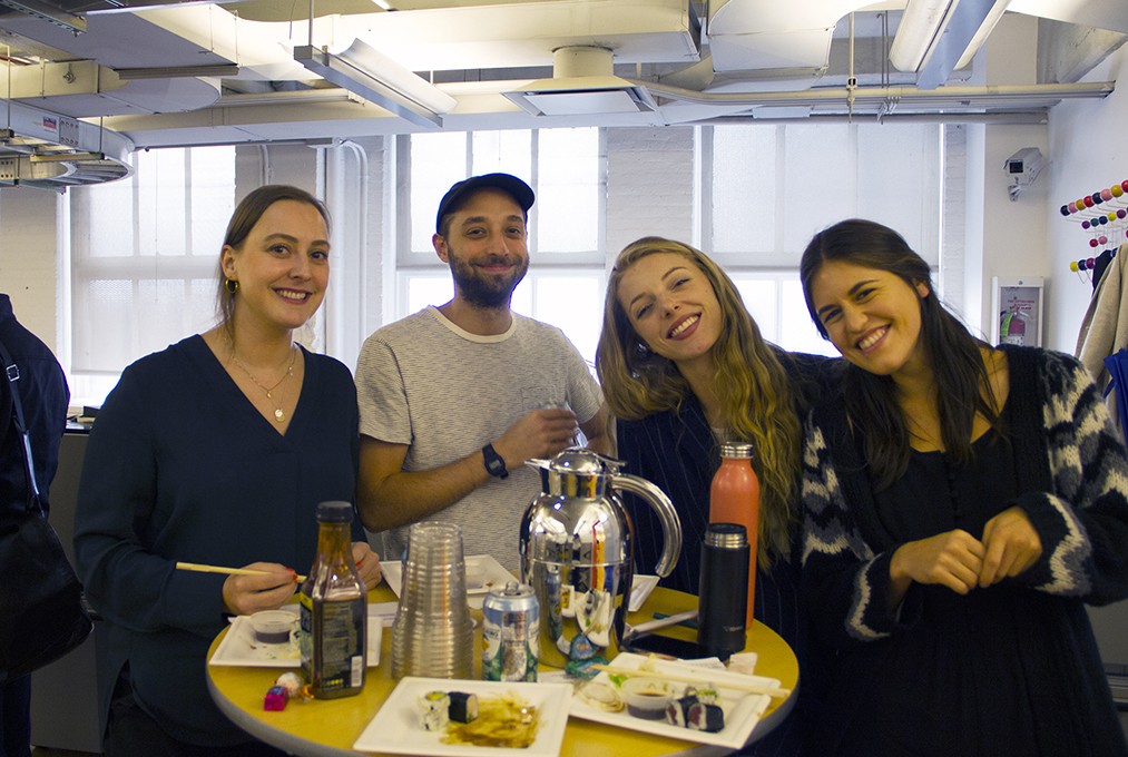 A photo of four people sitting in an office room, around a coffee table.
