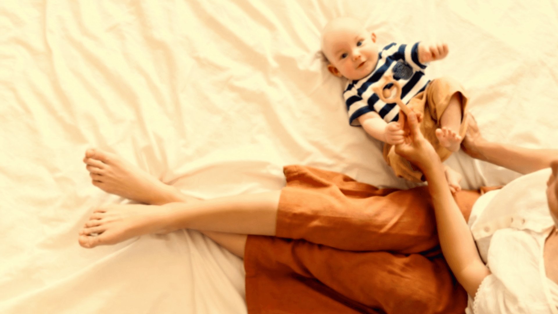 overhead shot of a woman playing with her baby on a bed