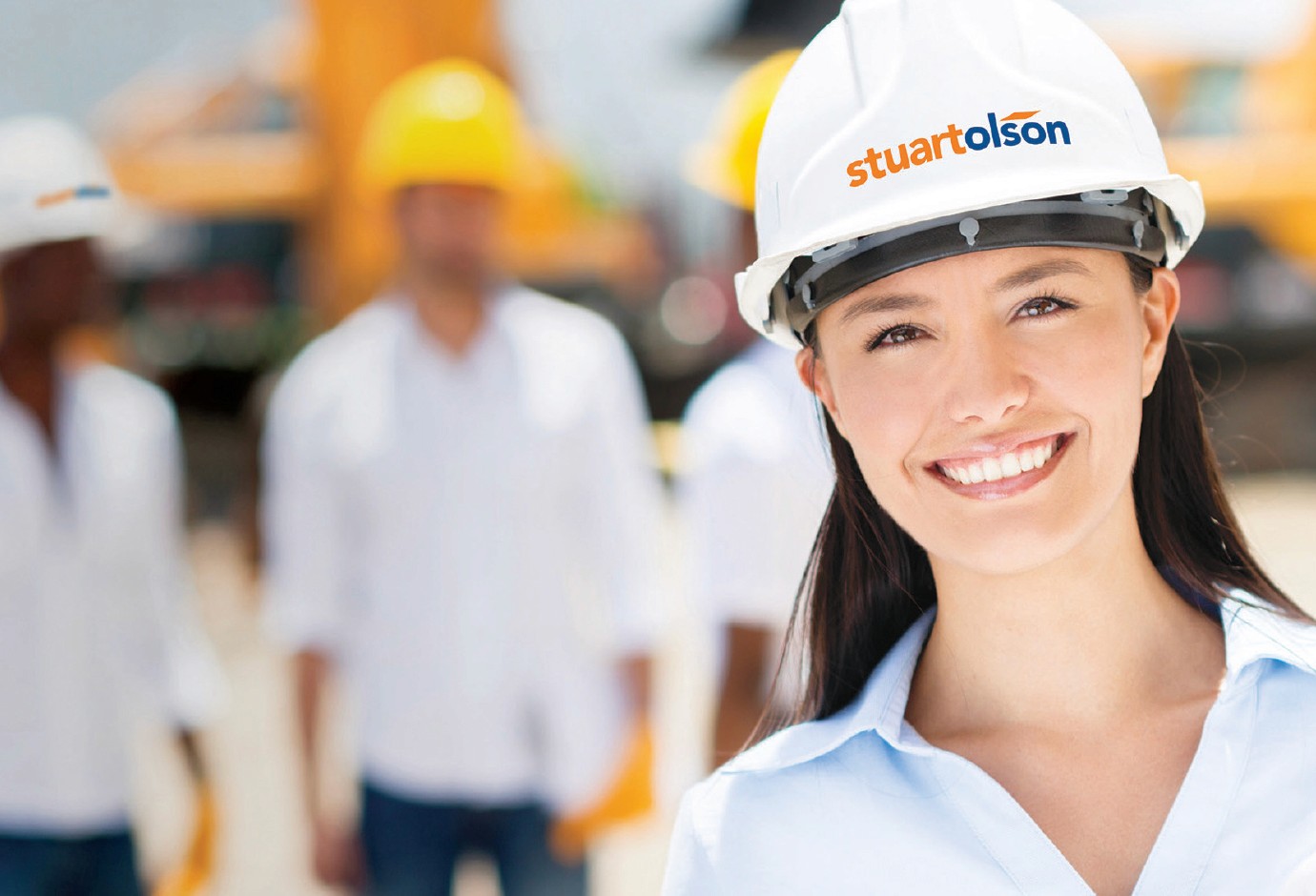 Professional woman wearing a Stewart Olson hard hat with people in the background