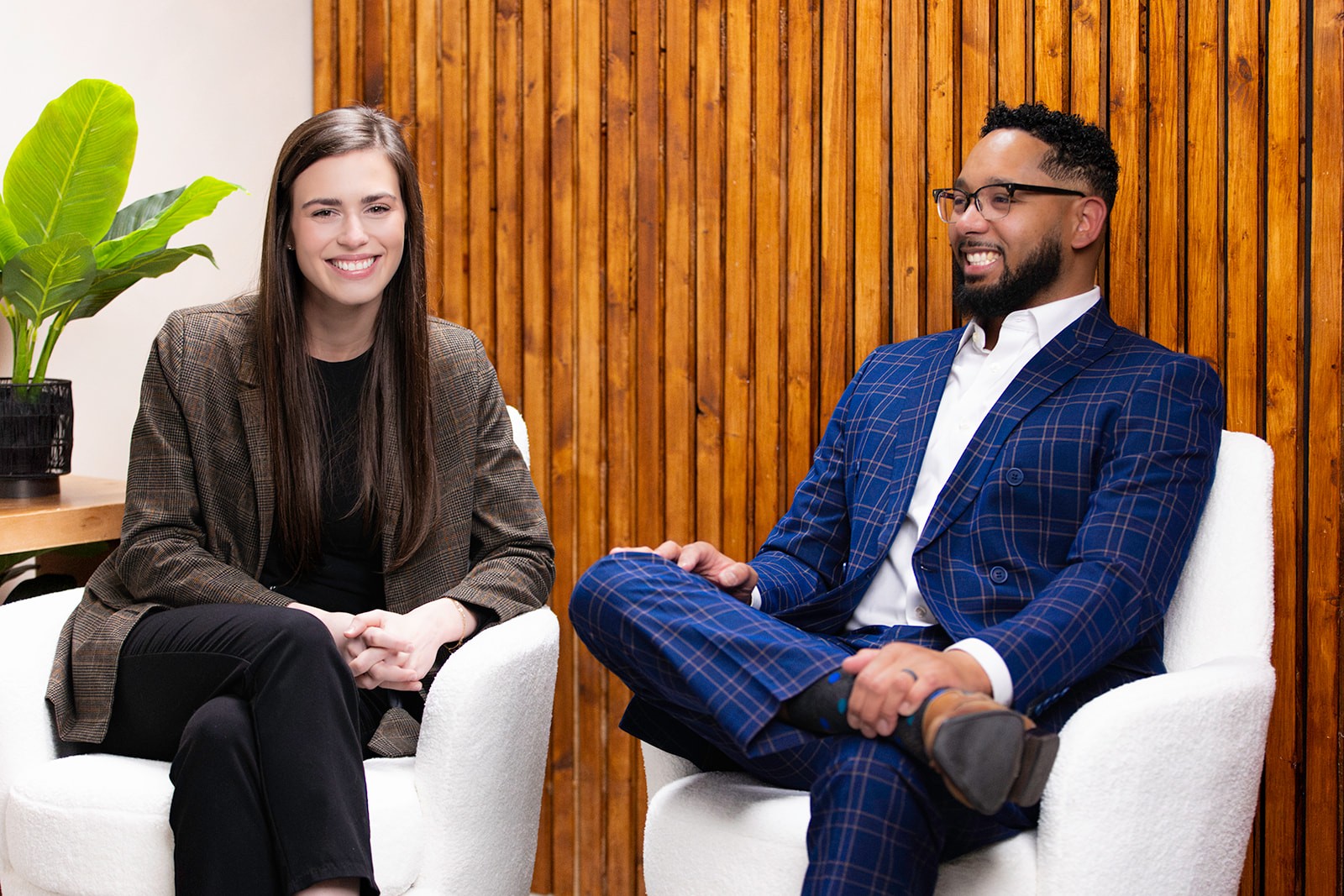 Chris Lewis and Kayley Morgan sit together in a modern office space, smiling during a conversation. The setting’s warm wood backdrop and natural light reflect the approachable, professional service offered by Chris Lewis Home Loans.