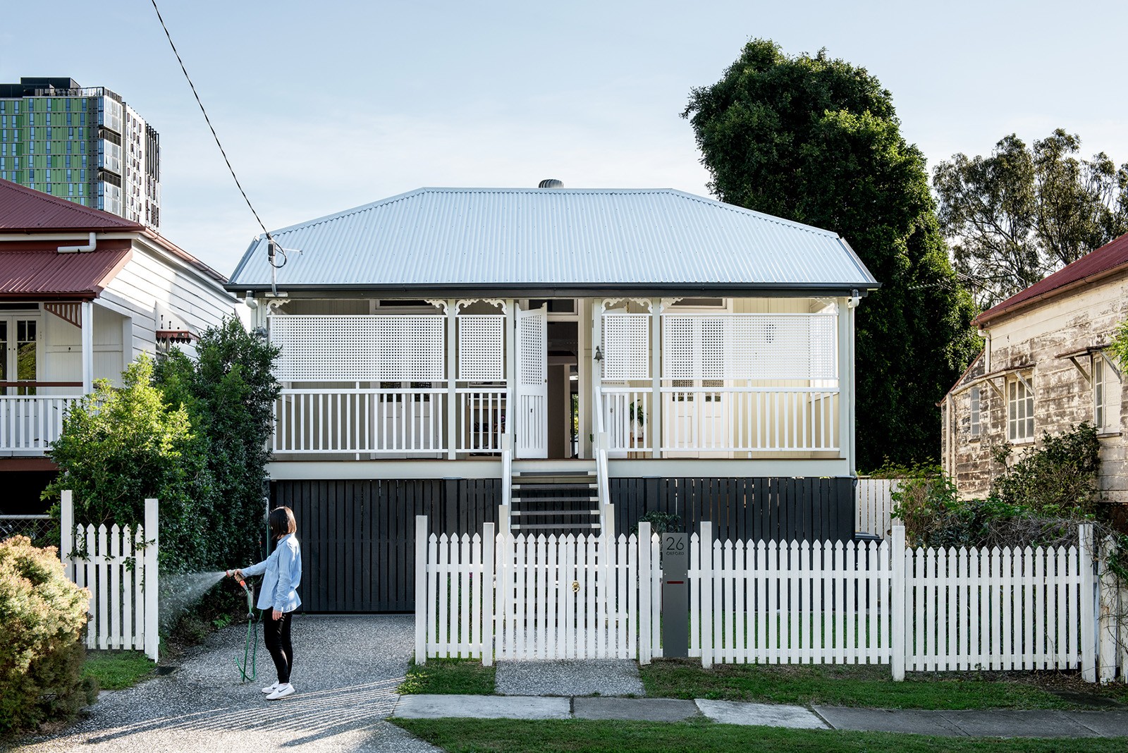 Street-facing view of Oxford Cottage, a restored Queenslander with a raised verandah, timber detailing, and a renewed connection to the suburban streetscape.