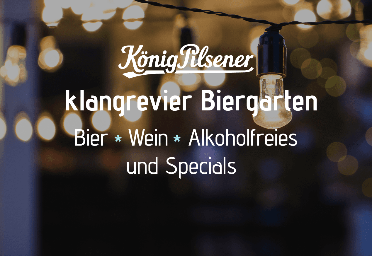 Stimmungsvolle Abendaufnahme mit warmen Lichterketten. Im Bild steht der Schriftzug ‚König Pilsener‘ sowie darunter ‚klangrevier Biergarten – Bier • Wein • Alkoholfreies und Specials‘