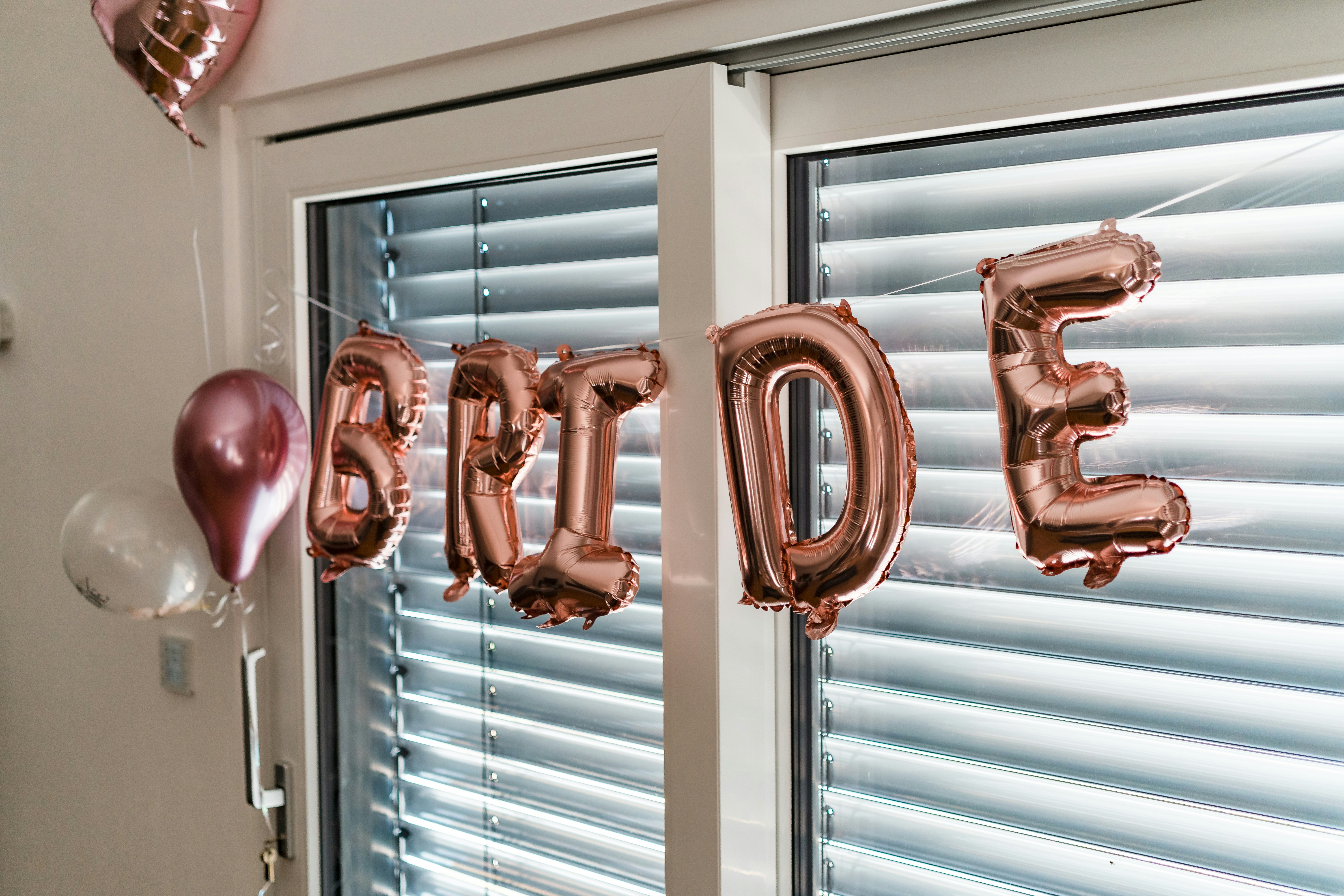 Rose gold letter balloons spelling bride in front of a window