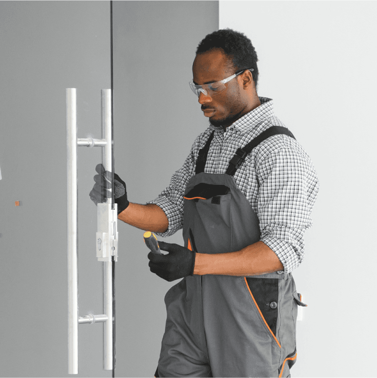 Technician measuring and aligning a door with a leveling tool.