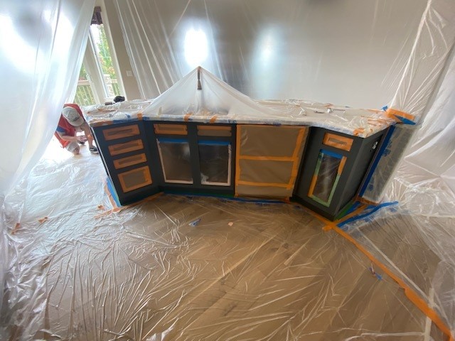 Kitchen cabinetry and island carefully masked and prepared during the refinishing process.