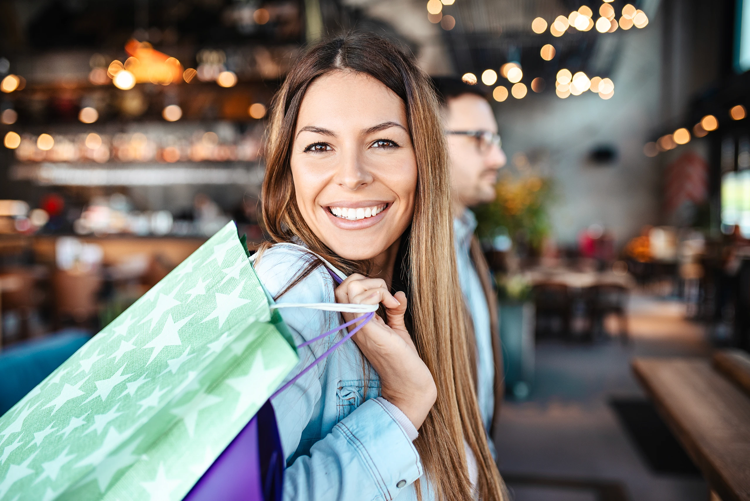 Smiling woman holding a shopping bag in a modern cafe interior