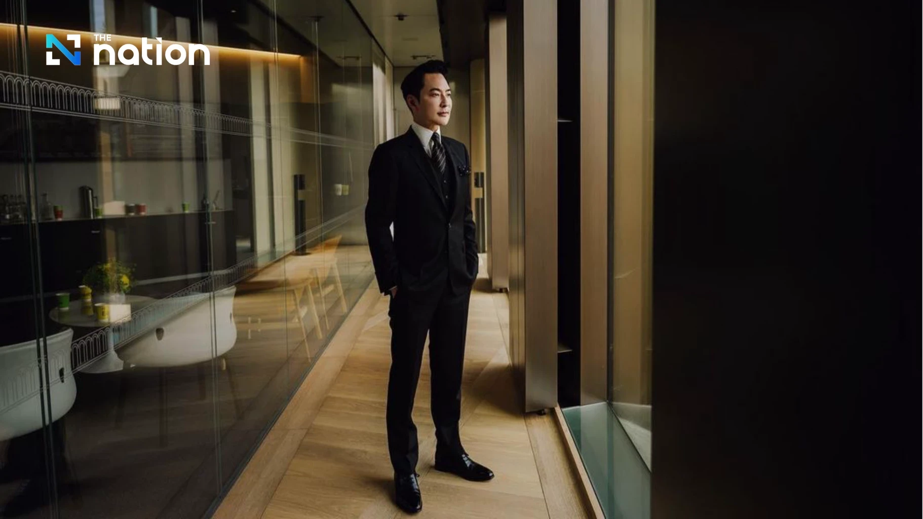 Calvin Lo in a suit standing in an office corridor