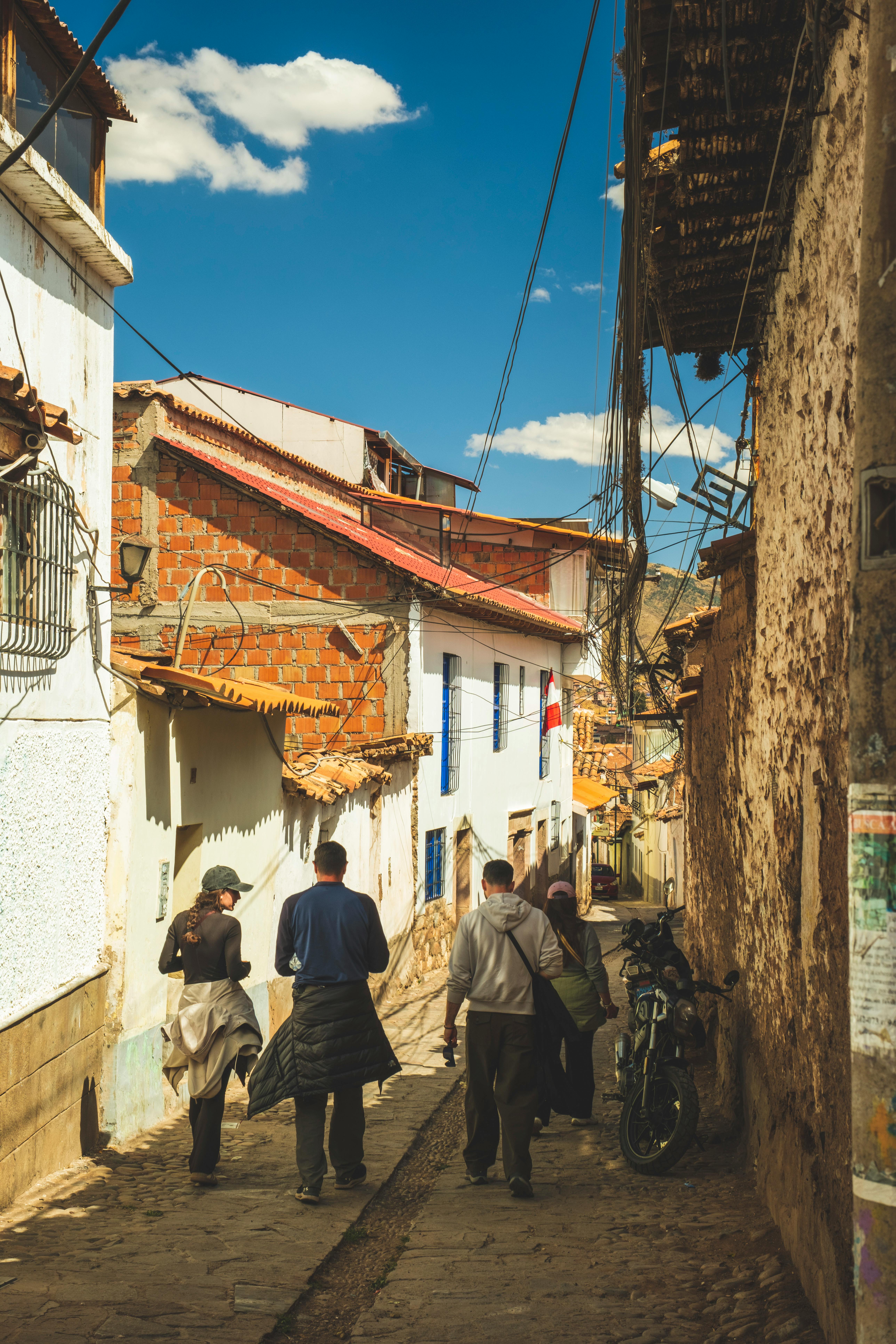 A smiling young man with crossed arms, wearing a plaid shirt and white t-shirt, poses against a dark background.