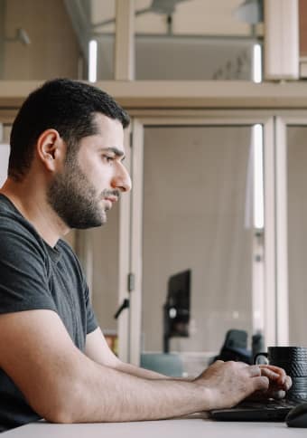 A man is sitting at a desk and working on his laptop.