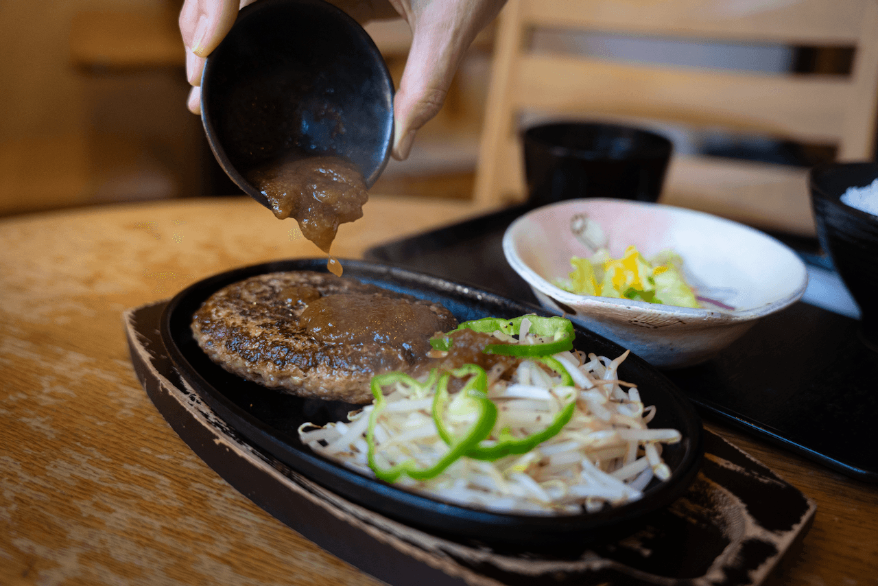 Sauce being poured over a hamburg
