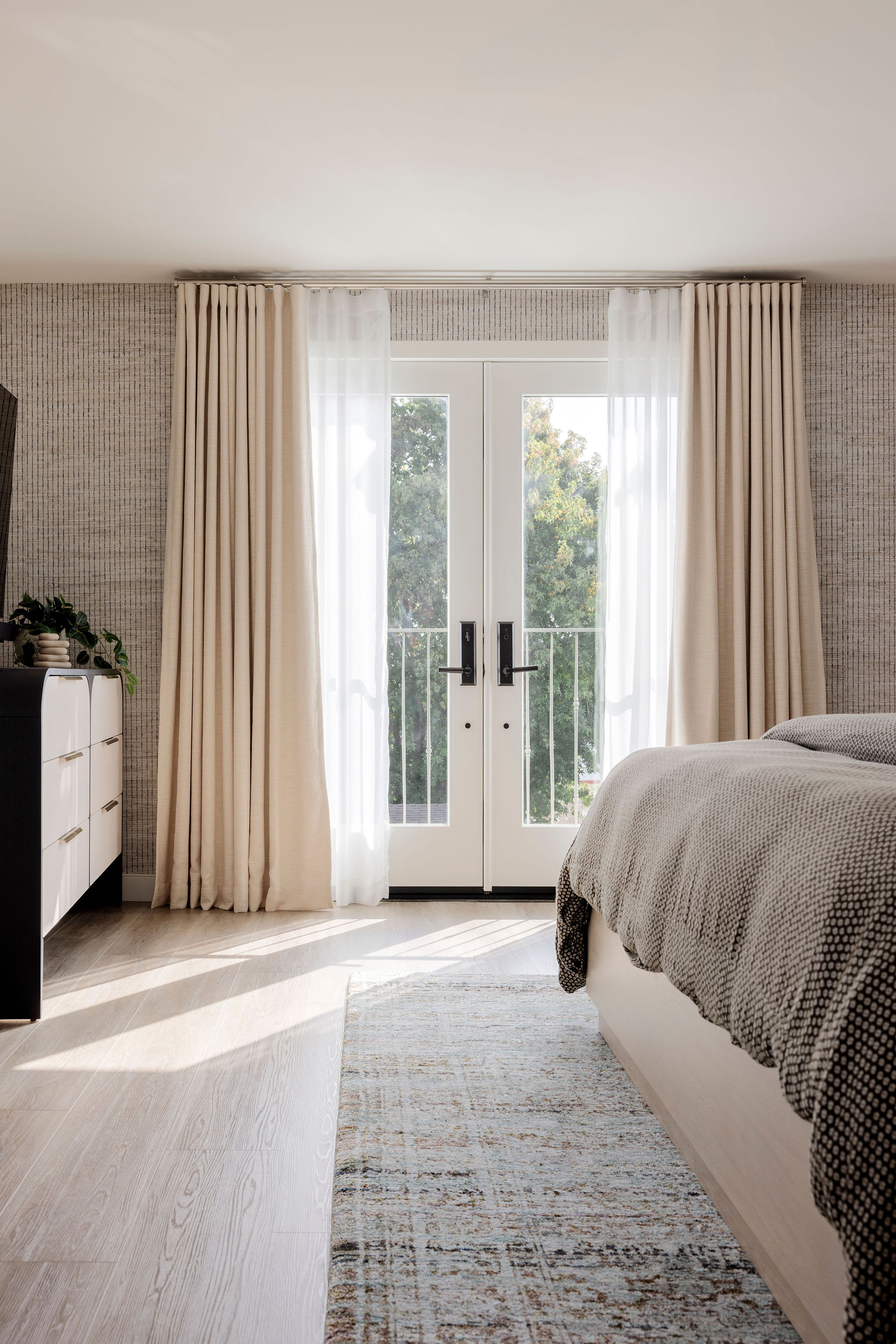 Relaxing bedroom with neutral tones and large balcony doors that let in natural light