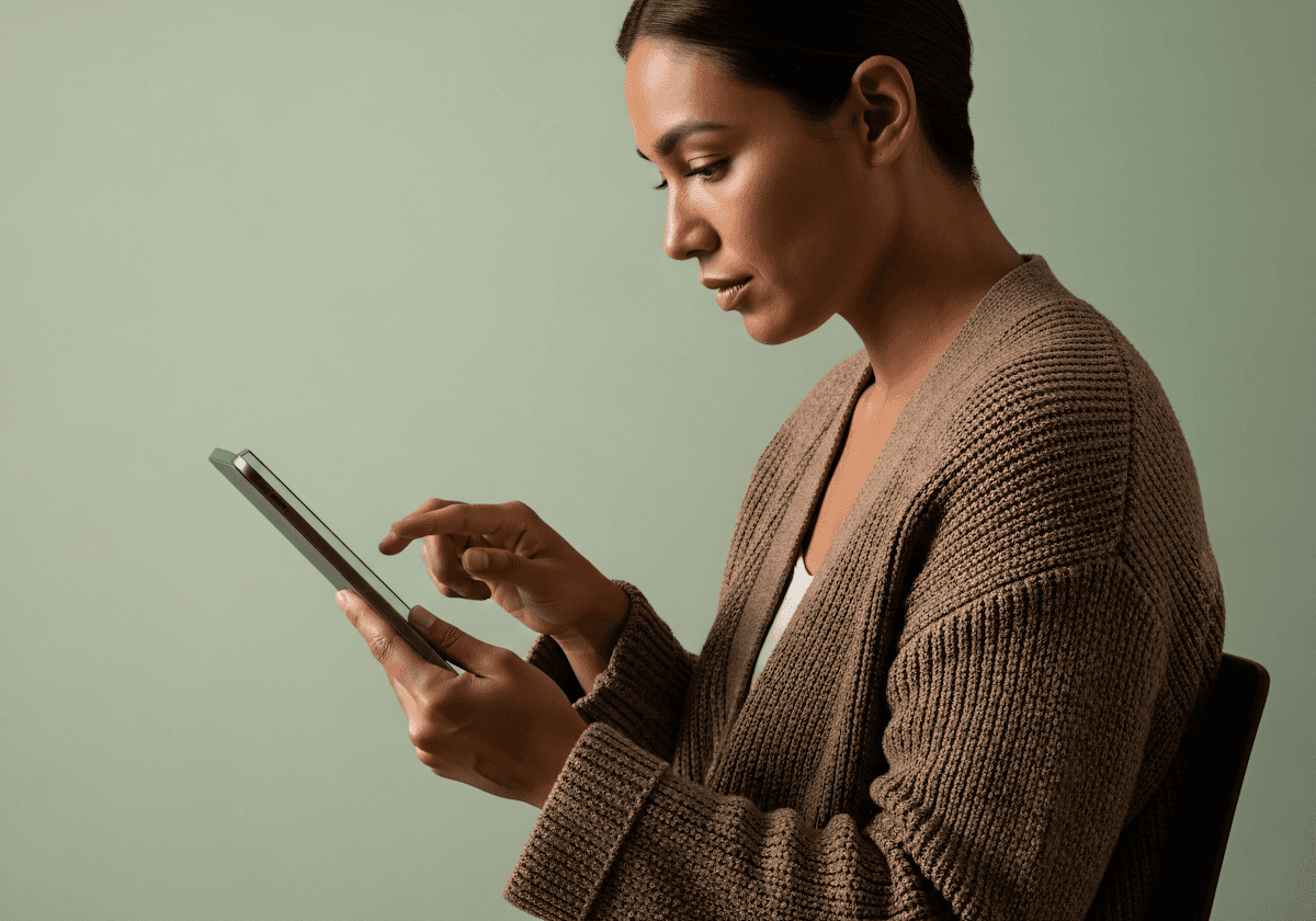 Relaxed young woman in white sweater lying down, smiling at colorful phone screen.