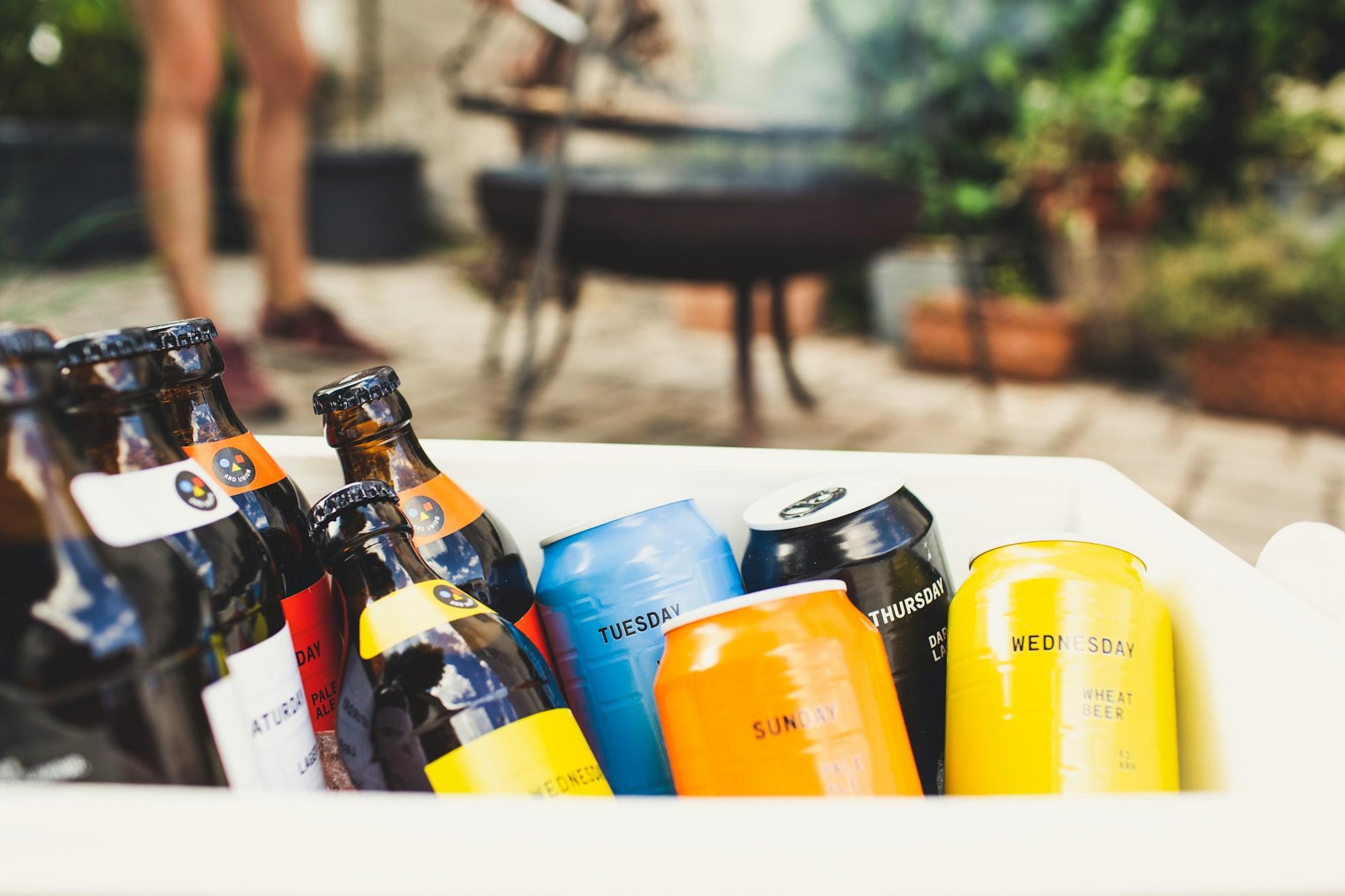 Bottles and brightly coloured cans of beer in an ice bucket at a garden party