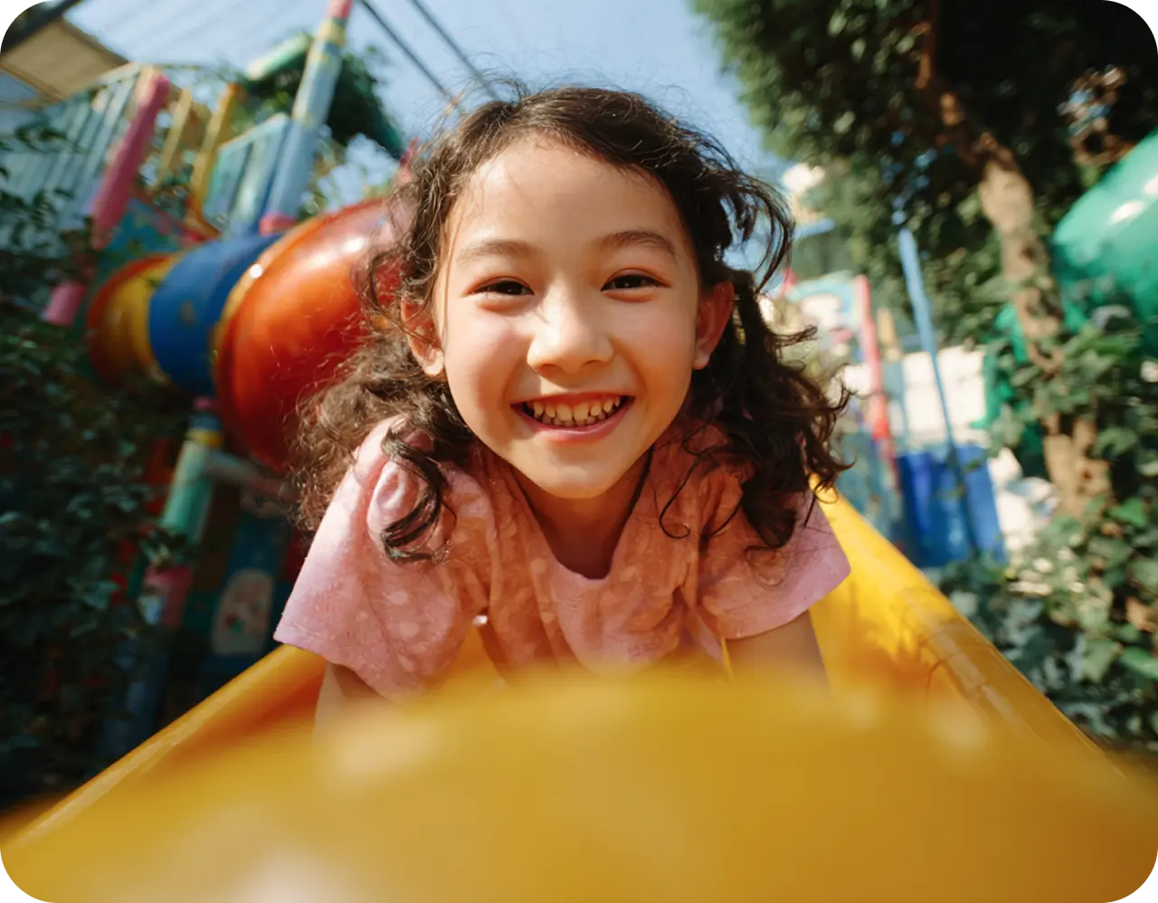 A joyful child smiles broadly, surrounded by iridescent bubbles in a sunlit garden, conveying a sense of happiness and playfulness.