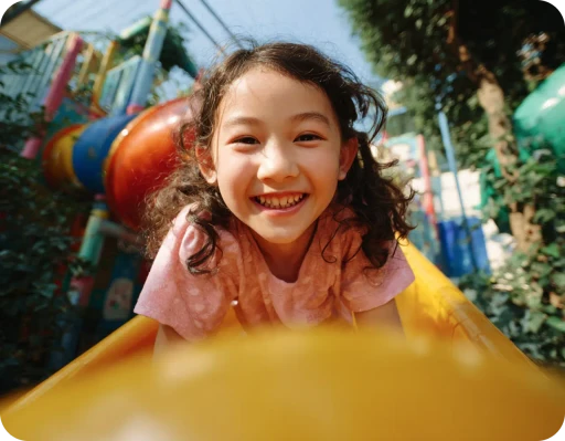 A joyful child smiles broadly, surrounded by iridescent bubbles in a sunlit garden, conveying a sense of happiness and playfulness.