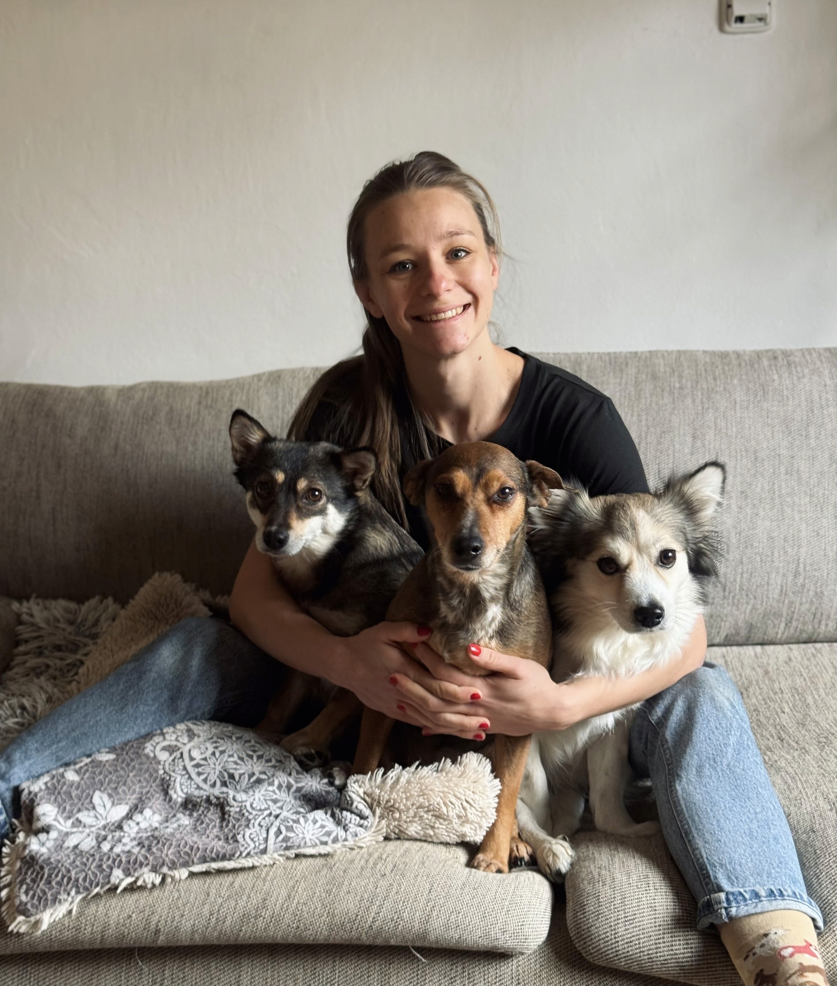 Couple sitting on a couch with a white poodle and a gray cat, creating a cozy and warm atmosphere