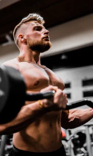 A man performs a focused bicep curl with a barbell during his workout