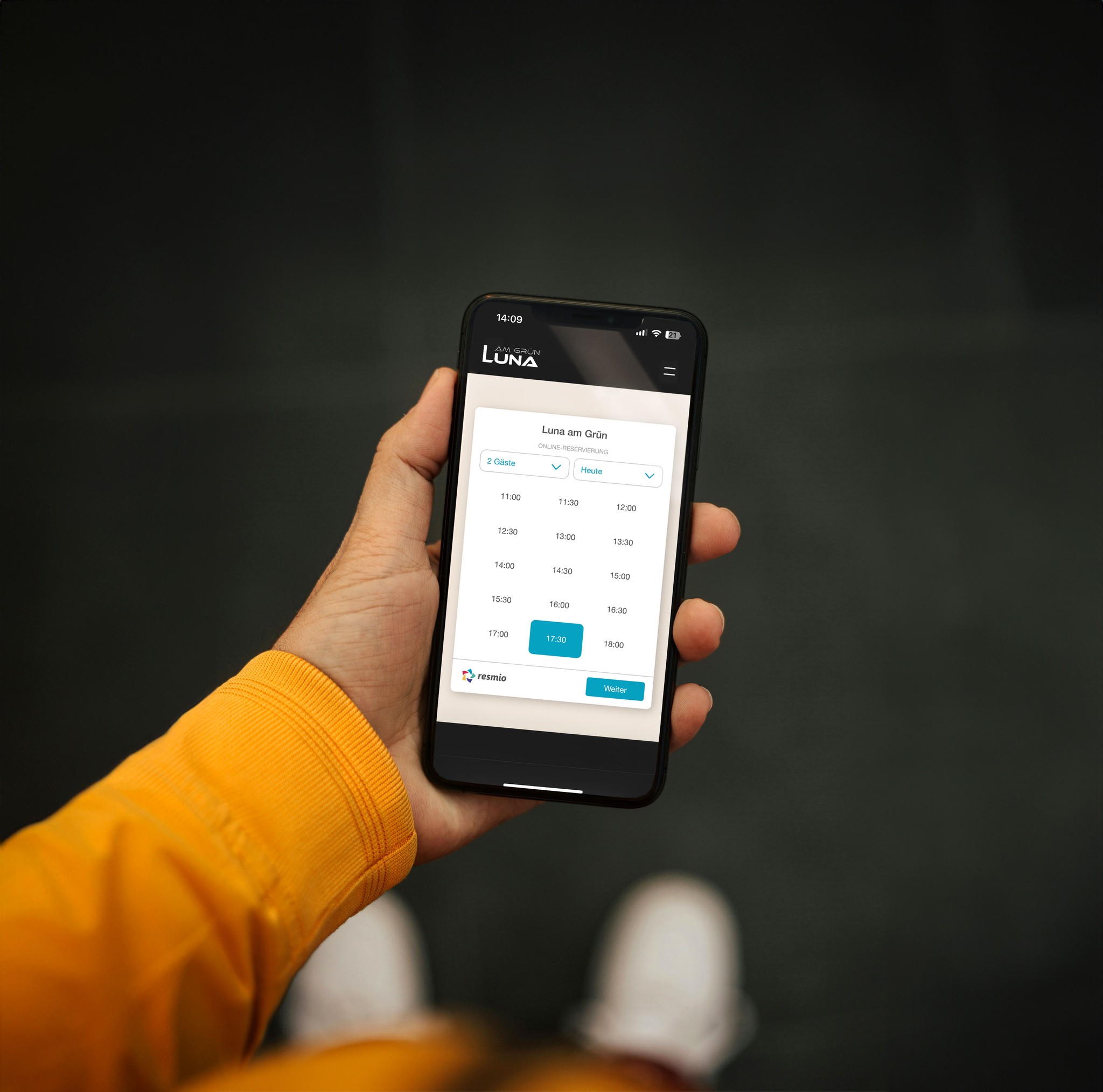 Person hält ein Smartphone, das den Online-Reservierungskalender des Restaurants Luna am Grün zeigt