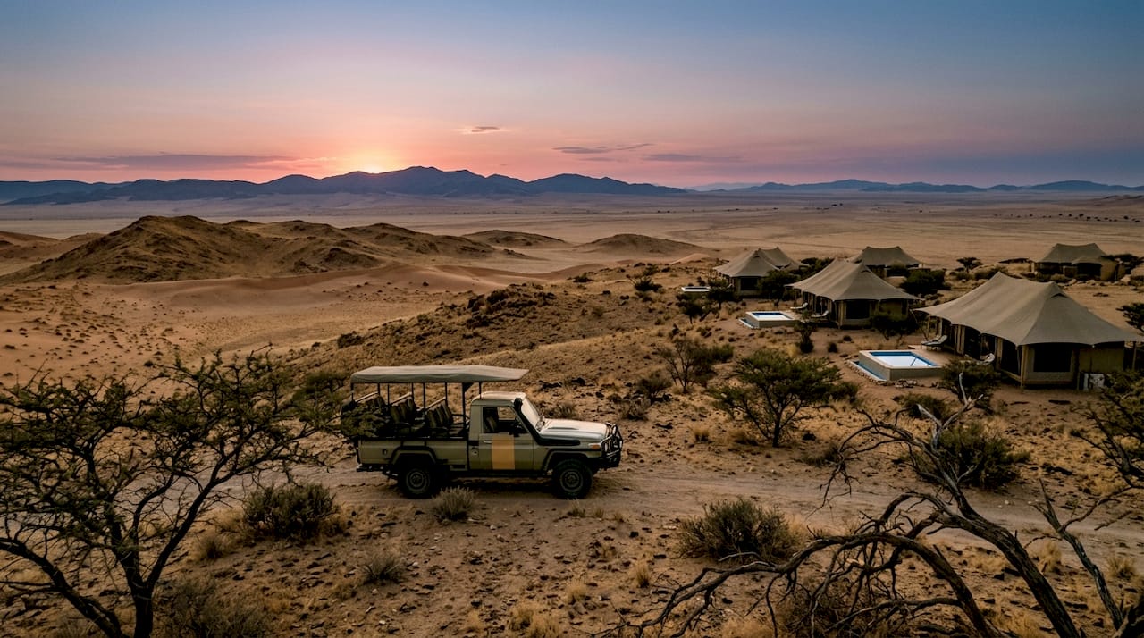 Safari vehicle and luxury tents at desert dusk