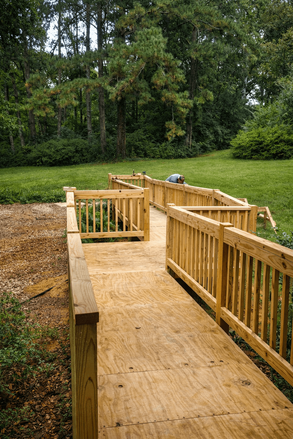 A modern, luxury beachfront villa with large glass windows and balconies overlooks a rocky shoreline, surrounded by palm trees at sunset.