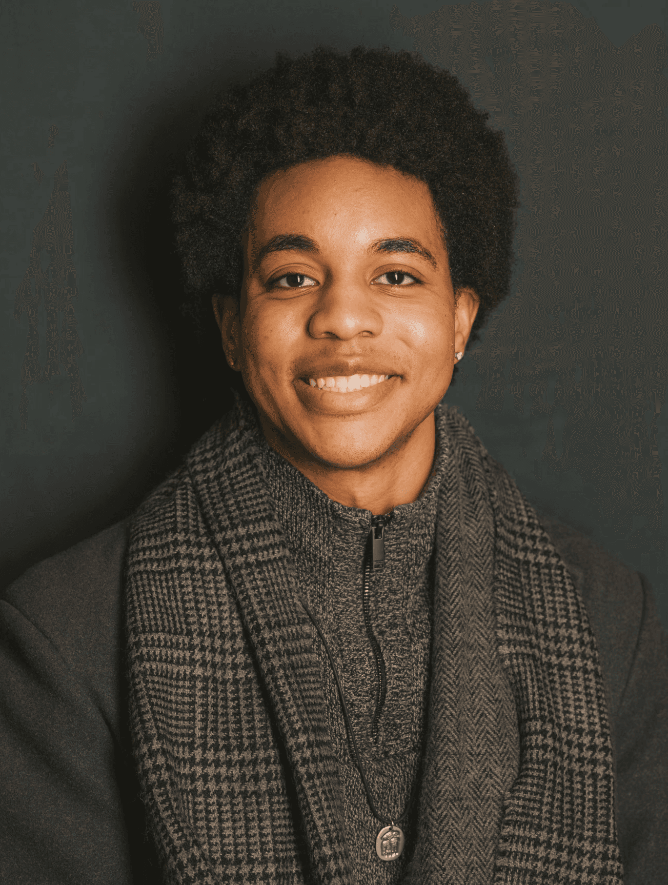 A thoughtful young person with dark hair gazes to the side, captured in soft black and white lighting.