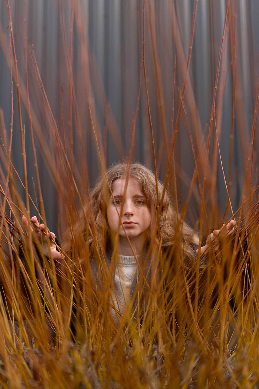 portrait jeune fille derrière branches oranges arbuste