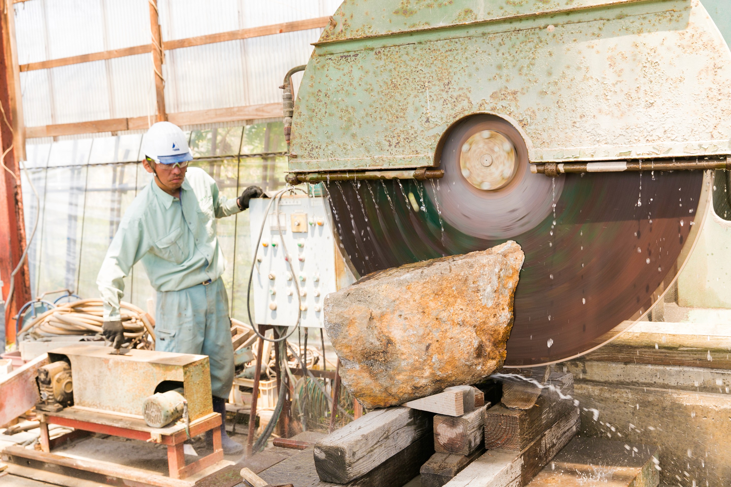 A large industrial saw cutting through a block of stone, with water lubrication to reduce friction and maintain cutting precision.