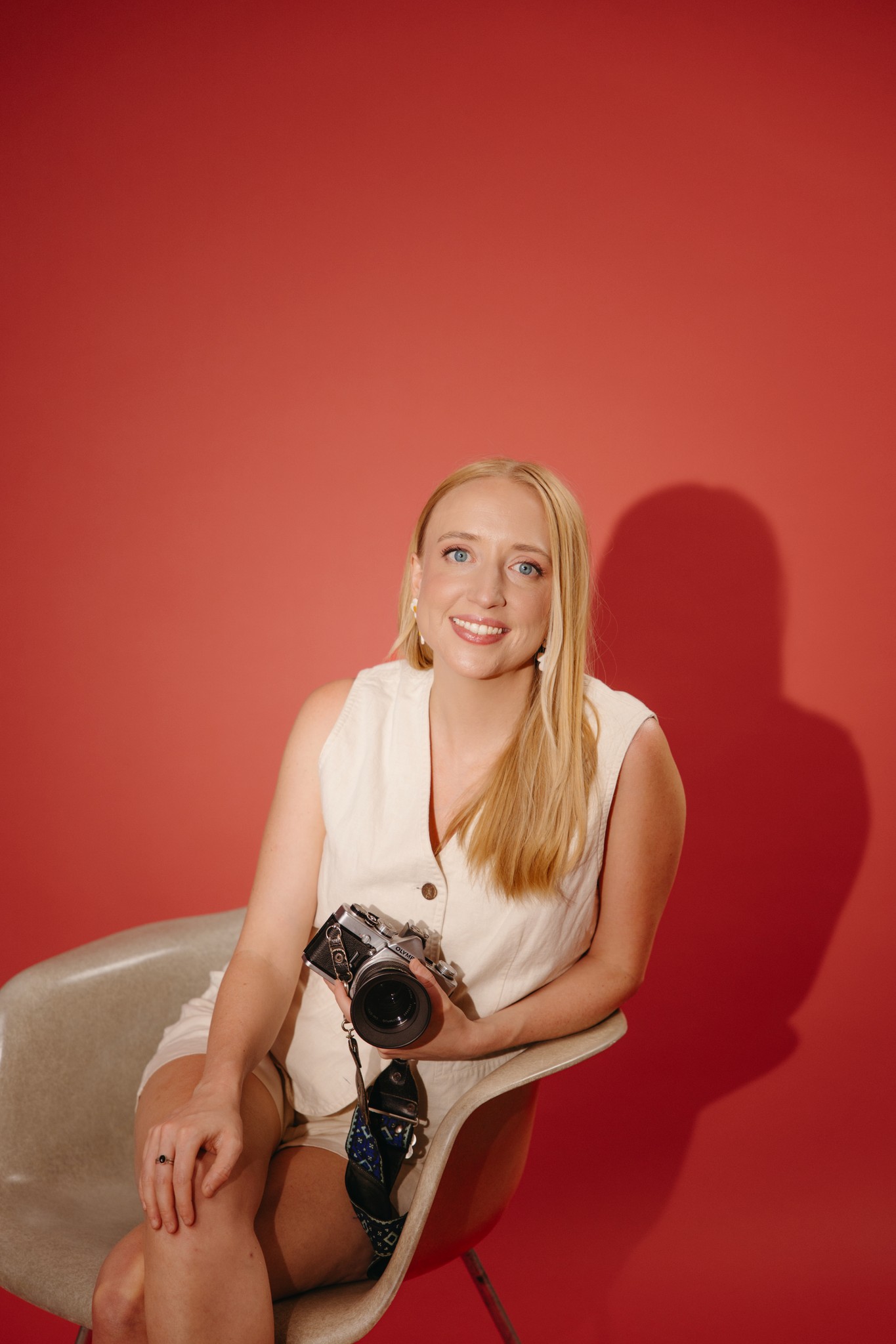 Headshot of Elise holding a camera on a red backdrop