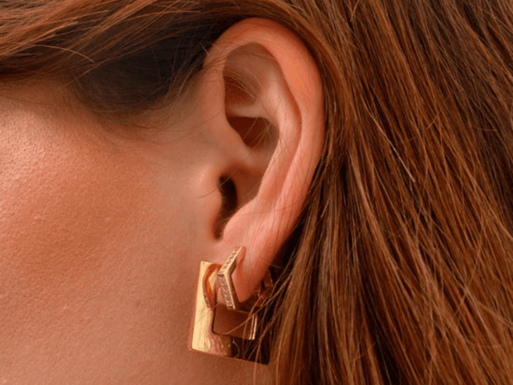 Femme portant une boucle d’oreille en or recyclé au design épuré, collection Kube Store.