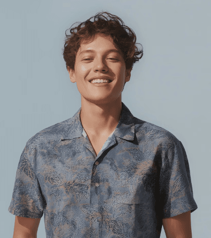 A young man in a coat smiling by looking infront