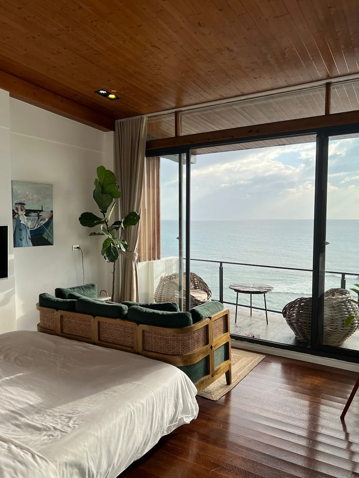 Family suite bedroom with a large bed, ocean view, and cozy seating beside glass doors.
