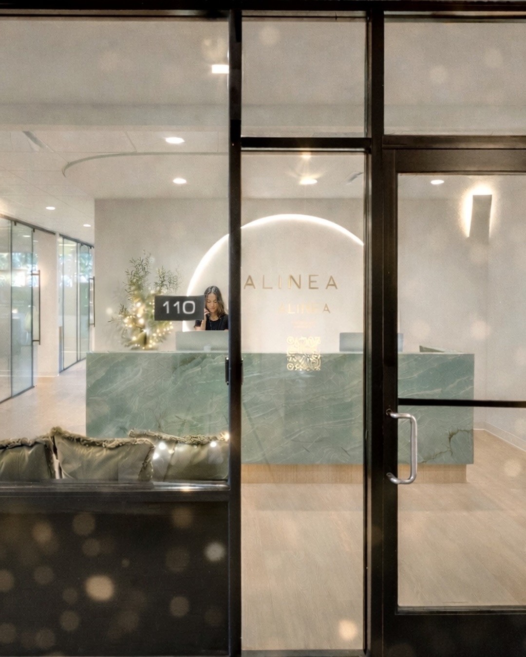 View into Alinea Orthodontics reception area showing illuminated reception signage and modern clinic interior.