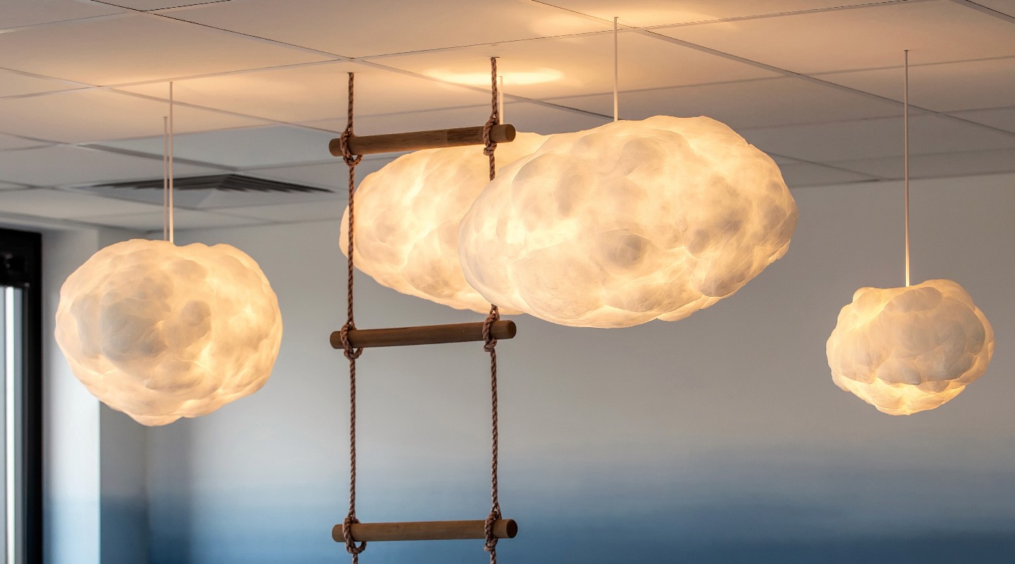 Suspensions lumineuses en forme de nuages éclairant une pièce, avec une échelle en bois pour l'accès.