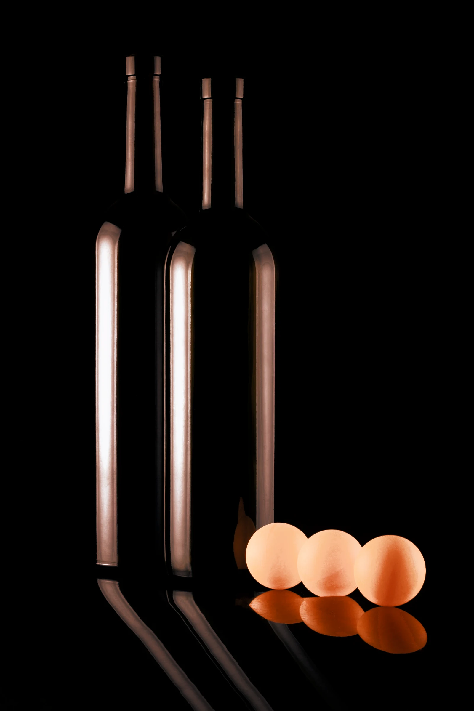 Two dark bottles with orange spheres