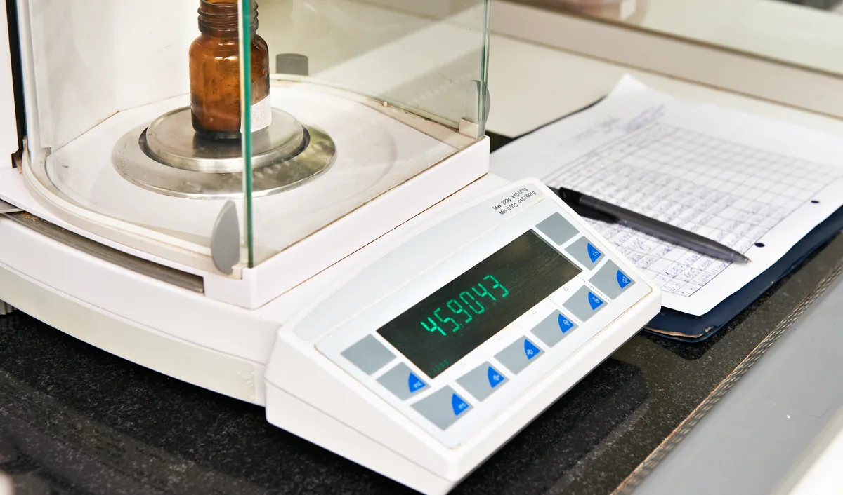 Laboratory balance beside a paper log sheet