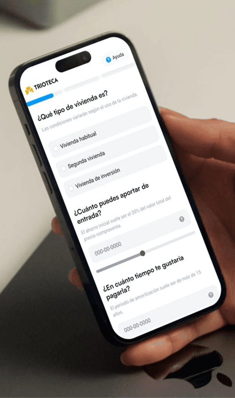This image shows a person holding a smartphone displaying a financial application with options for selecting types of housing, including "Vivienda habitual," "Segunda vivienda," and "Vivienda de inversión," alongside sliders for inputting entry amount and preferred payment duration.
