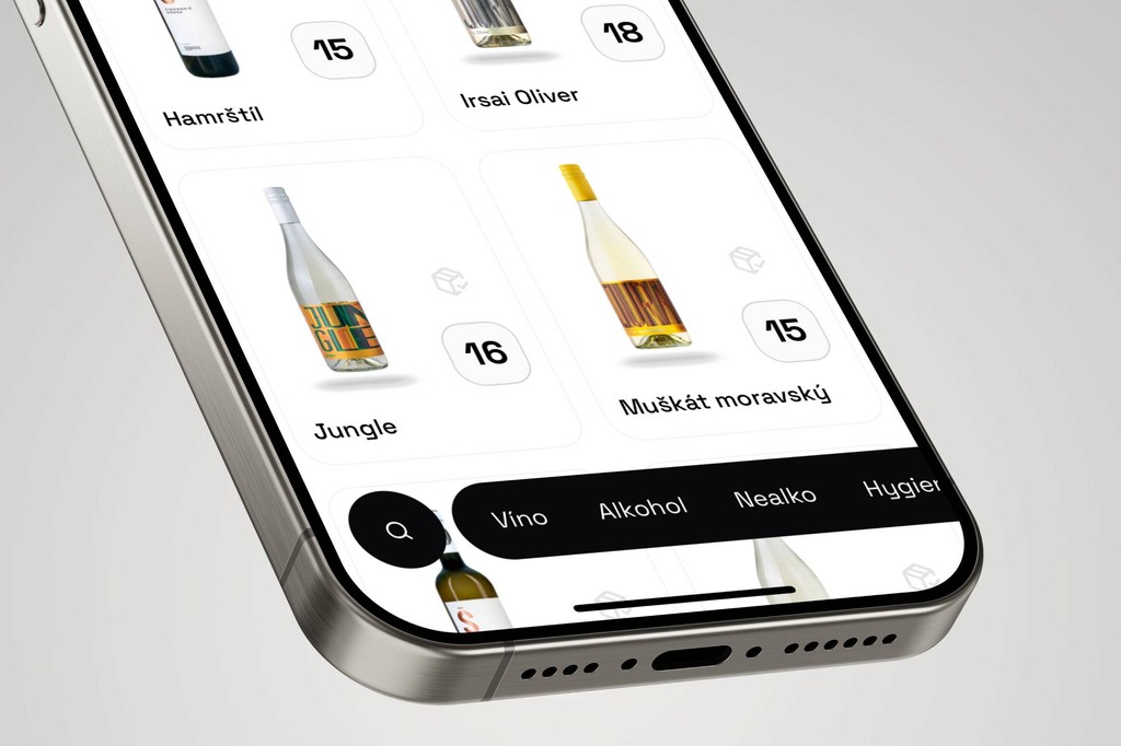 Close-up of a smartphone screen displaying a wine selection app with a minimalist white interface, showing wine bottles labeled ‘Jungle’ and ‘Muškát moravský’ along with stock numbers, and a black navigation bar with category filters at the bottom.