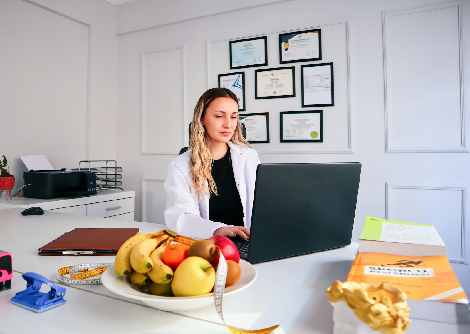 A registered dietitian working at a laptop beside a bowl of fresh fruit, representing personalized, one-on-one virtual nutrition support.