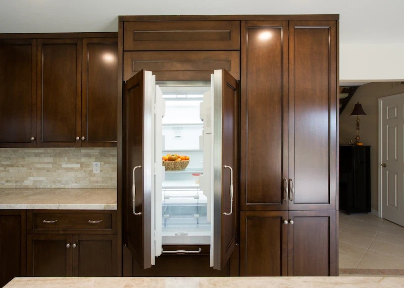 Close-up of kitchen with dark wood cabinets and refrigerator door open in Orange Interior Remodel.