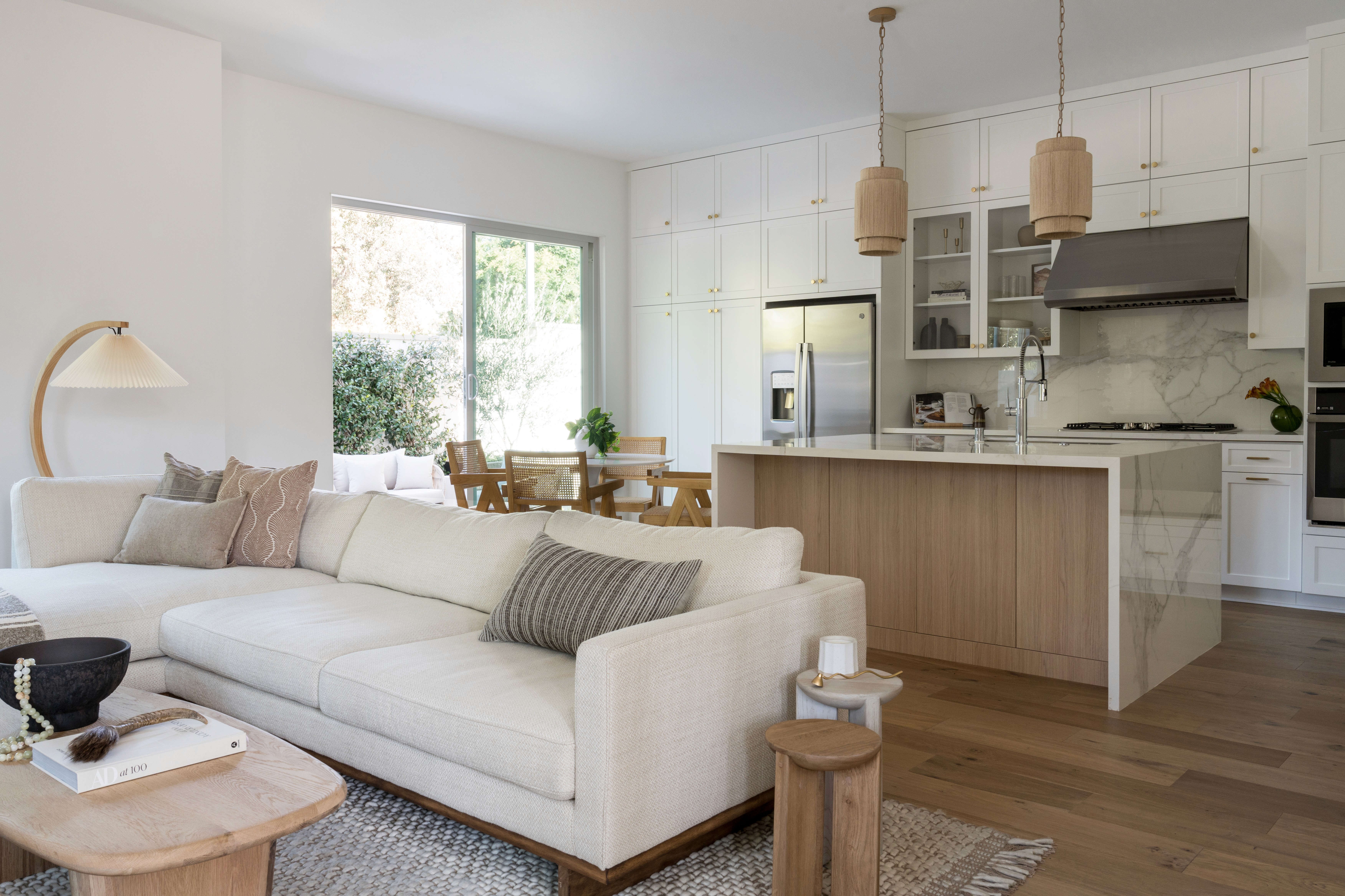 Open concept living room and kitchen with white linen couch and light wood tones by Jubilee Interiors in Arcadia, California