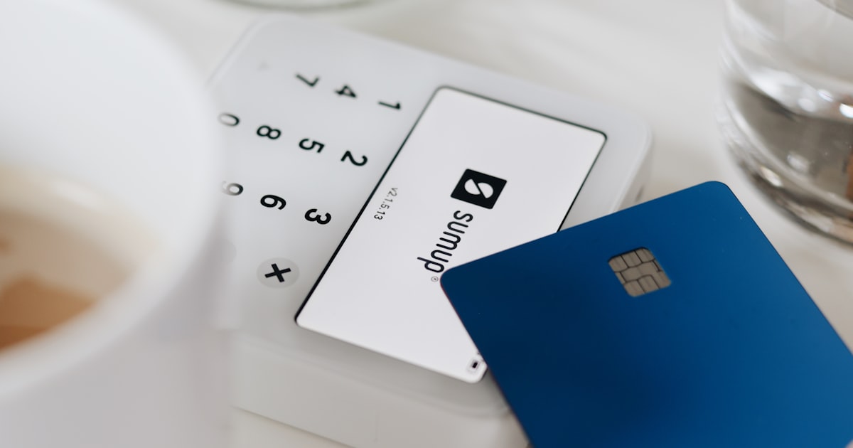 A credit card resting next to a cup of coffee on a cafe table, capturing everyday spending decisions.