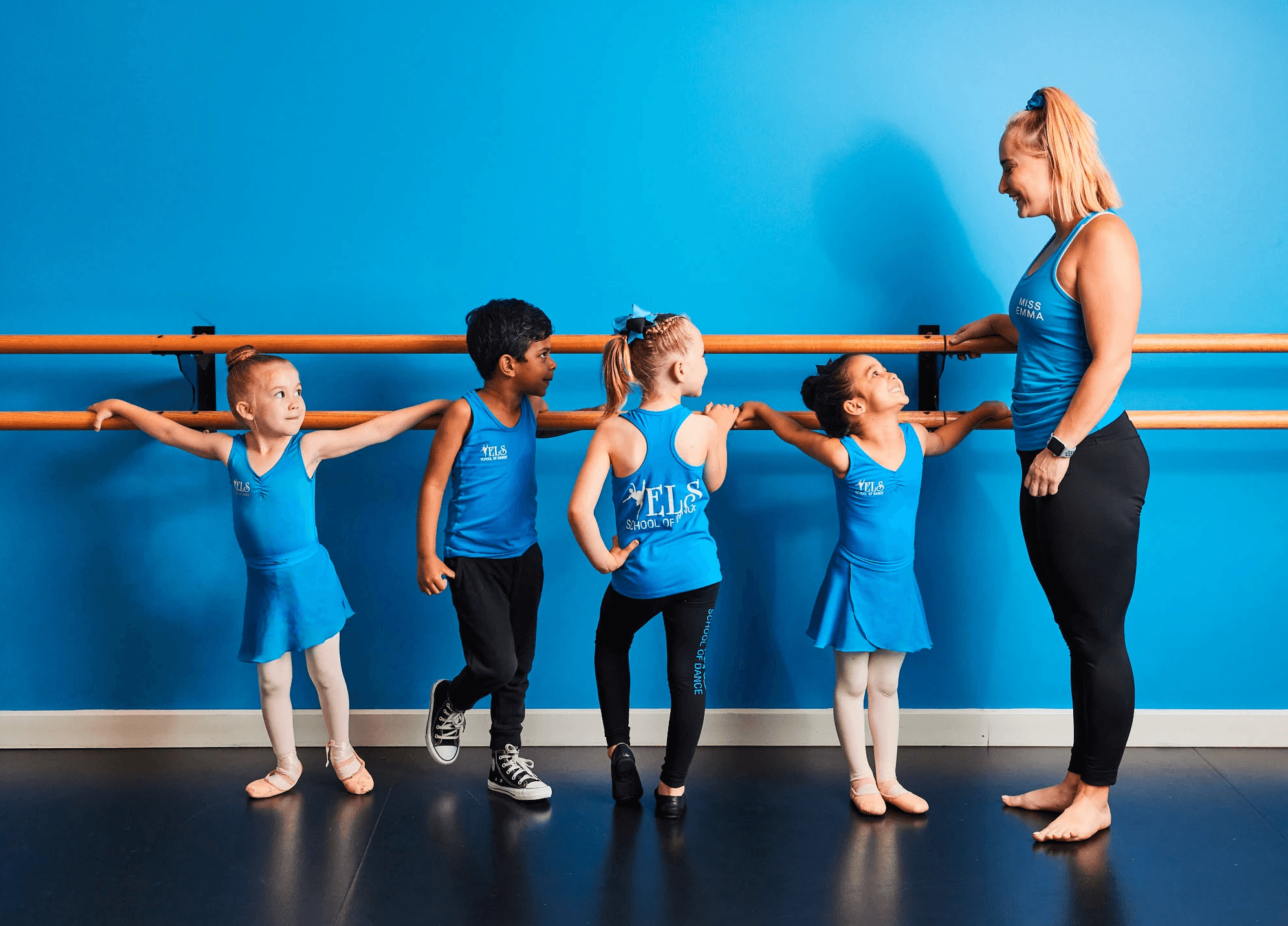 dancers standing at barre with teacher