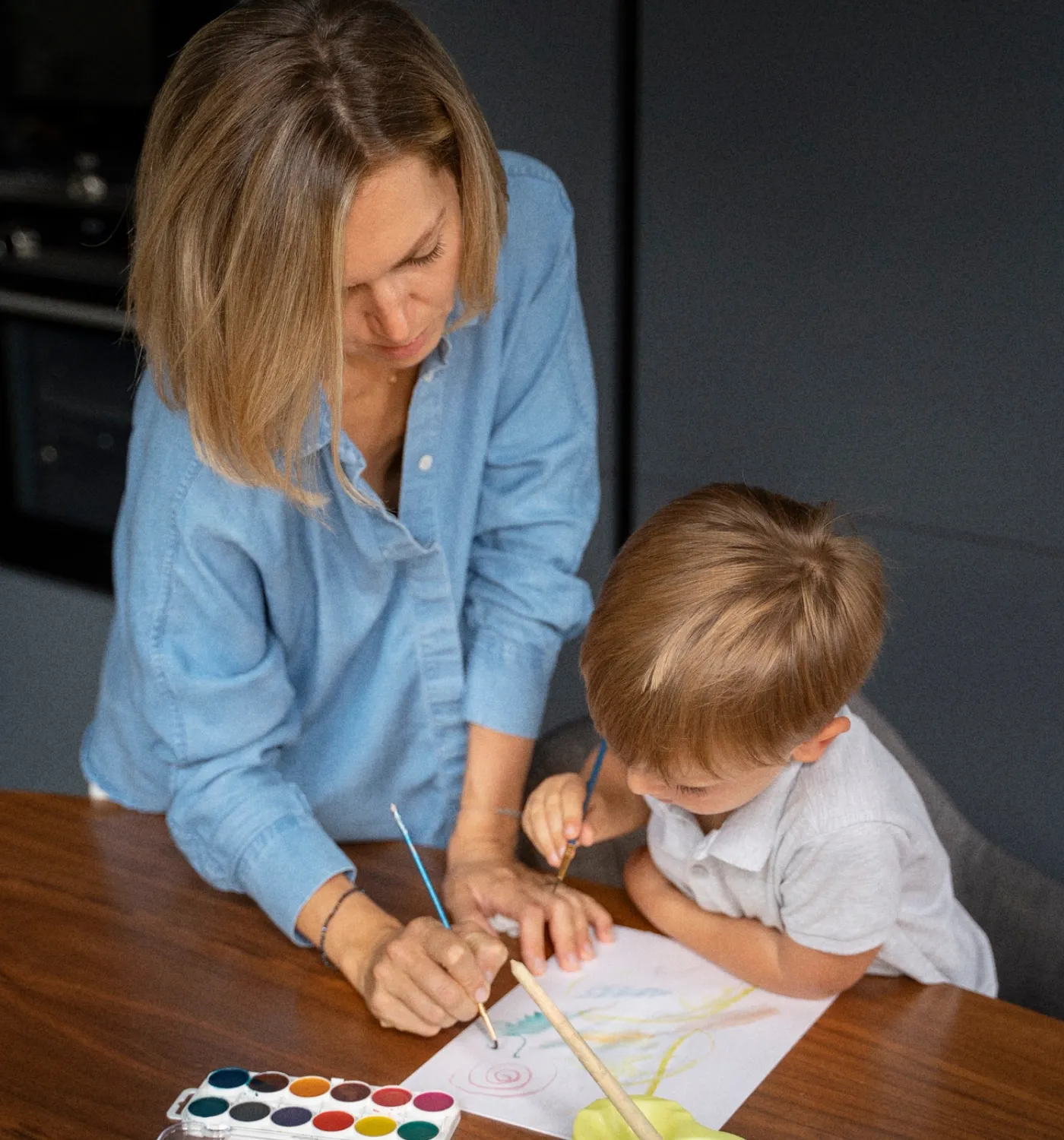 A child painting with watercolors on the floor during a play-based therapy session