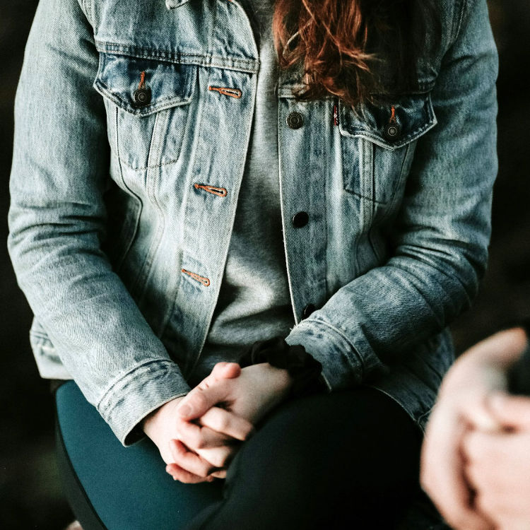 teenager sitting with her hands clasped together in her lap