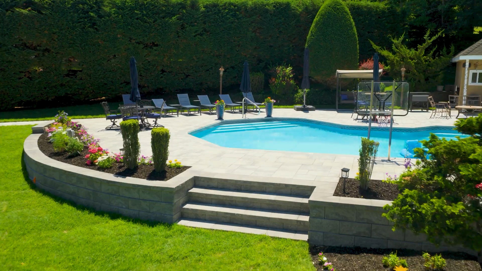 Luxury backyard resort with pool and paver deck by Rockville Concrete Corp