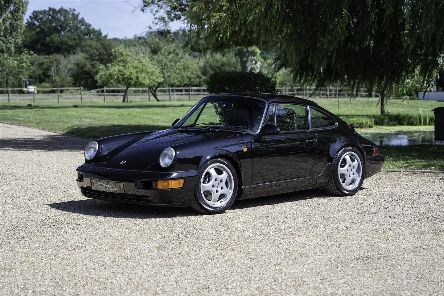 Porsche 964 RS Lightweight in deep black, front three-quarter view on gravel