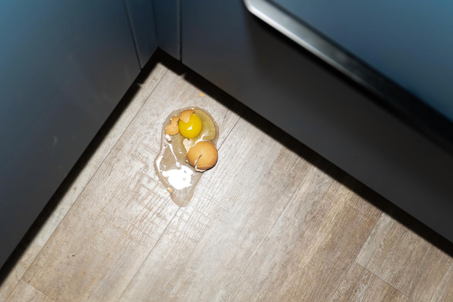 Cracked egg on hybrid kitchen flooring, highlighting stain-resistant, easy-clean surfaces suited for everyday Queensland living.