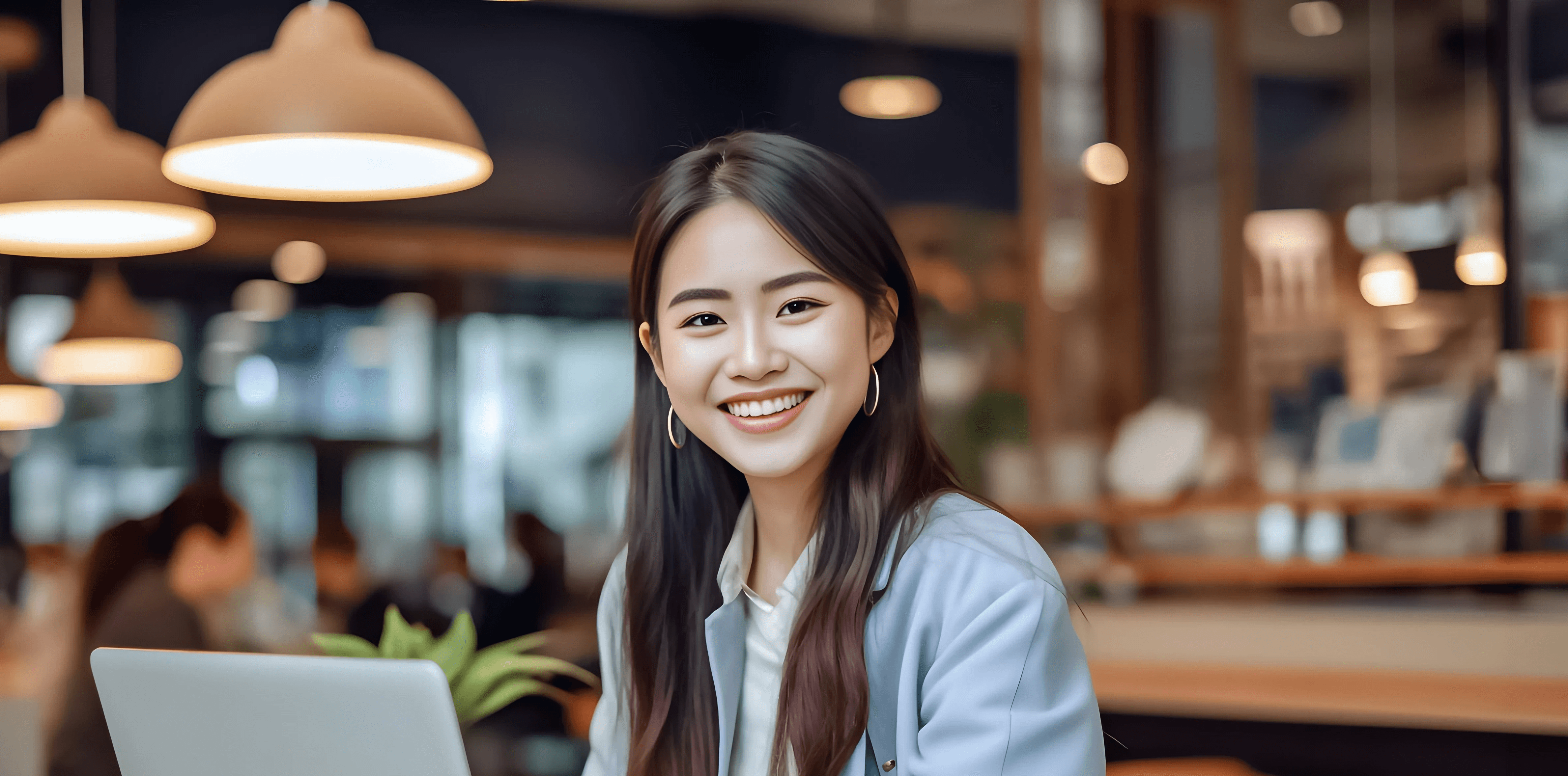Headshot of Tiffany, a smiling young professional woman working on a laptop in a cafe.