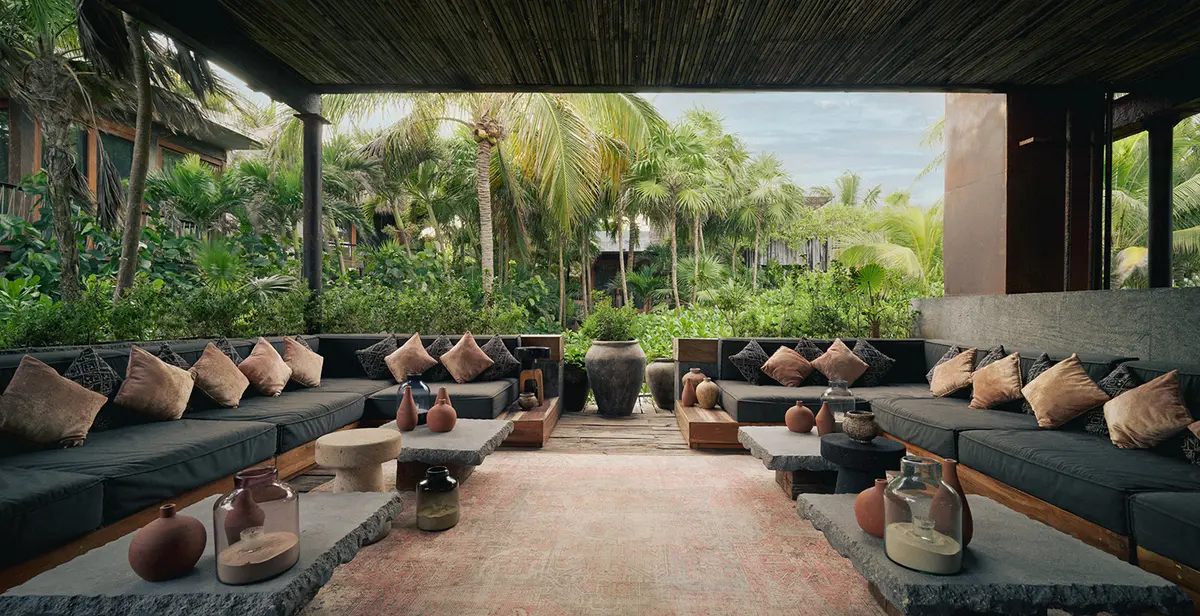 Sky Terrace restaurant at Be Tulum: covered terrace amidst jungle and palm trees, featuring spacious seating with large sofas and 4 center tables.